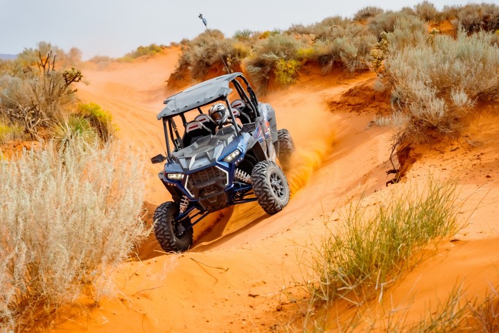 a person riding a UTV down a sand road